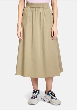 Khaki, mellemlang nederdel med elastisk talje, lavet af letvægtigt stof. Sammen med multikolorede sneakers med snørebånd.