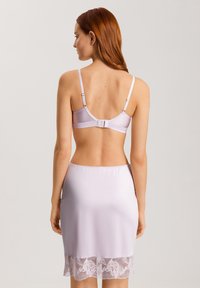 Sävyinen lilac-lingeriesetti, joka sisältää sileän, satiinimaisen brasierin säädettävillä olkaimilla ja pitsireunuksilla varustetun liukuhameen, korostaen herkkiä yksityiskohtia.