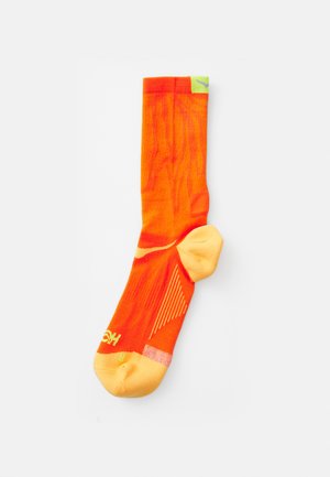 Calzino sportivo arancione brillante con la punta e il tallone di un giallo chiaro. Presenta motivi testurizzati e linee diagonali per grip e stile.