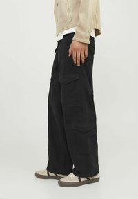 Pantaloni cargo negri cu picioare largi, având multiple buzunare laterale și un material din bumbac texturat. Accentuati cu o croială relaxată.