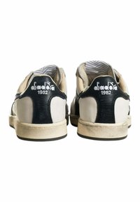 Sneakers in pelle bianca e nera con un pannello posteriore testurizzato, suola in gomma e logo sul tallone; presentano una fodera interna a motivo.
