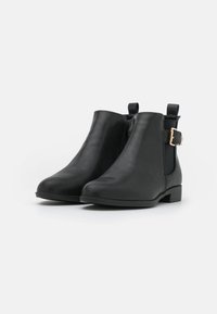 Bottines en cuir noir avec une texture lisse, fermeture éclair sur le côté, panneaux élastiques et une boucle décorative sur le côté extérieur. Talon bas en bloc.