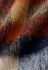 Tissu texturé présentant un mélange d'orange chaud, de bleu marine profond et de beige, avec une texture douce et duveteuse et des motifs abstraits et mélangés.