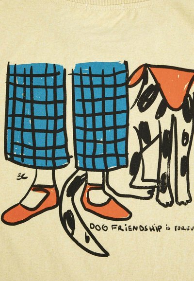 Jambes en pantalon à carreaux bleus et chaussures rouges à côté d'un chien tacheté avec une oreille rouge et une queue enroulée autour d'une jambe. Le texte indique "amitié canine".