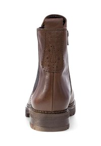 Botín de cuero marrón con paneles laterales elásticos, puntera redonda, perforaciones decorativas en la parte trasera y un tacón bajo apilado.
