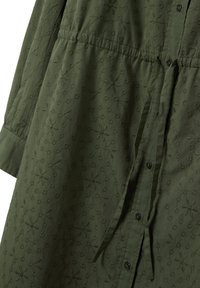 Olivengrünes Kleid aus Baumwolle mit floraler Stickerei, Knopfleiste, langen Ärmeln und geraffter Taille. Hat eine strukturierte Oberfläche.