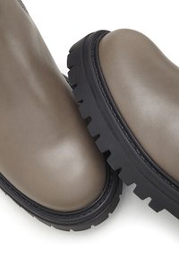 Chunky enkelboots in taupe leer met een ronde neus en zwarte gestructureerde rubberen zool. Gladde oppervlakte met zichtbare stiksels.