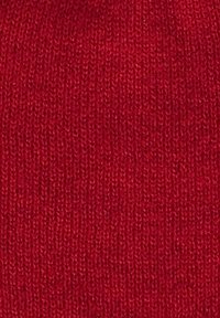 Tessuto a maglia di colore rosso brillante con una consistenza fine, caratterizzato da un motivo uniforme. Nessun hardware o accessori notevoli visibili.