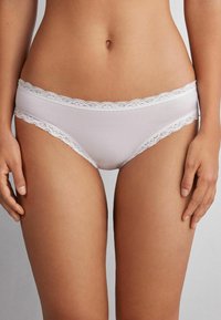 Witte katoenen bikini-onderbroeken met een delicate witte kantafwerking langs de bovenrand. Gladde textuur en een lage taille.