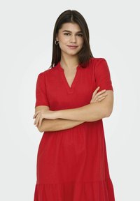 Vestido de lino rojo con mangas cortas, escote en V y falda de capas. Textura suave con un corte holgado, adecuado para un estilo casual.
