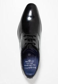 Chaussure habillée en cuir noir avec une finition brillante et un bout pointu. Dispose de six oeillets et d'une semelle intérieure bleue avec une marque et des informations sur la taille.