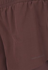 Shorts de sport bordeaux en tissu doux et texturé avec une taille élastique. Logo "ENDURANCE" en blanc sur le bas à droite.