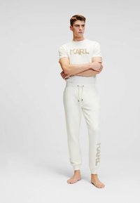 Heren lounge set in crème met een shirt met korte mouwen featuring een beige "KARL" logo en bijpassende joggingbroeken met een elastische tailleband en boorden.