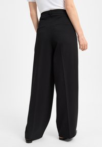 Zwarte wijde pantalons met een hoge taille, gestructureerd ontwerp, twee achterzakken en een gladde textuur, gecombineerd met een witte blouse.