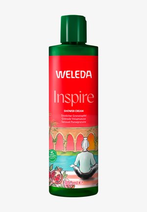 Weleda Inspire brusecreme i en 400 ml grøn flaske med en rød etiket, der har granatæbleillustrationer og detaljer om en spa-scene.
