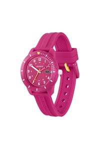 Montre en silicone rose avec un cadran rond, des marqueurs d'heure blancs et une aiguille des secondes jaune. Présente le logo Lacoste et un bracelet texturé.