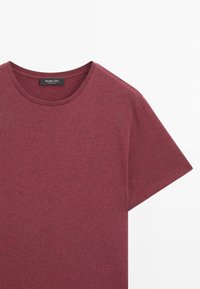 T-shirt in cotone bordeaux con scollo rotondo, maniche corte e una consistenza morbida. L'etichetta all'interno del colletto riporta "Massimo Dutti".