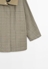 Plaid patterned jacket in shades of beige and brown with a contrasting solid collar and long sleeves.