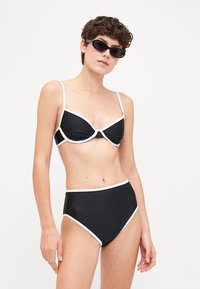 Čierny bikiny set s bielym lemovaním; top v štýle braletky a vysokopásové spodky; hladká textúra; minimalistický dizajn; bez viditeľných vzorov.