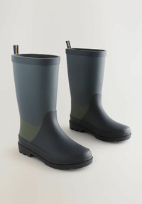Bottes de pluie en caoutchouc vert foncé, hautes, avec des semelles noires et des anses de traction, présentées côte à côte sur un fond clair.