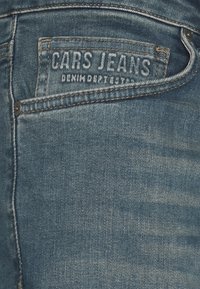 Blauwe denim jeans met een gestructureerde afwerking. Bevat een gestikte "CARS JEANS" label op de achterzak en een metalen knoopdetail.