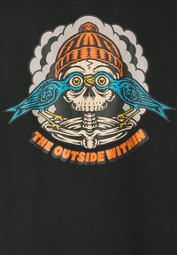 Zwarte shirt met een kleurrijke afbeelding van een schedel die een oranje muts draagt, geflankeerd door twee blauwe vogels, met de tekst "THE OUTSIDE WITHIN".