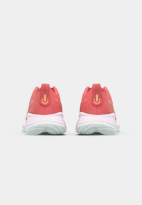 Baskets de sport roses avec une tige texturée, semelle blanche et accents réfléchissants. Comprend une languette à l'arrière pour un enfilage facile.
