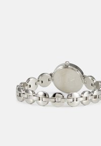 Orologio in acciaio inossidabile argento con cassa rotonda, bracciale a maglie circolari e incisione sul retro. Presenta una finitura semplice e lucida su tutta la superficie.