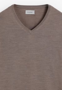 V-Ausschnitt-Pullover in Taupe, aus softem Stoff gefertigt. Mit gerippten Bündchen und Saum, sowie einem kleinen, auf der Brust gestickten Logo.