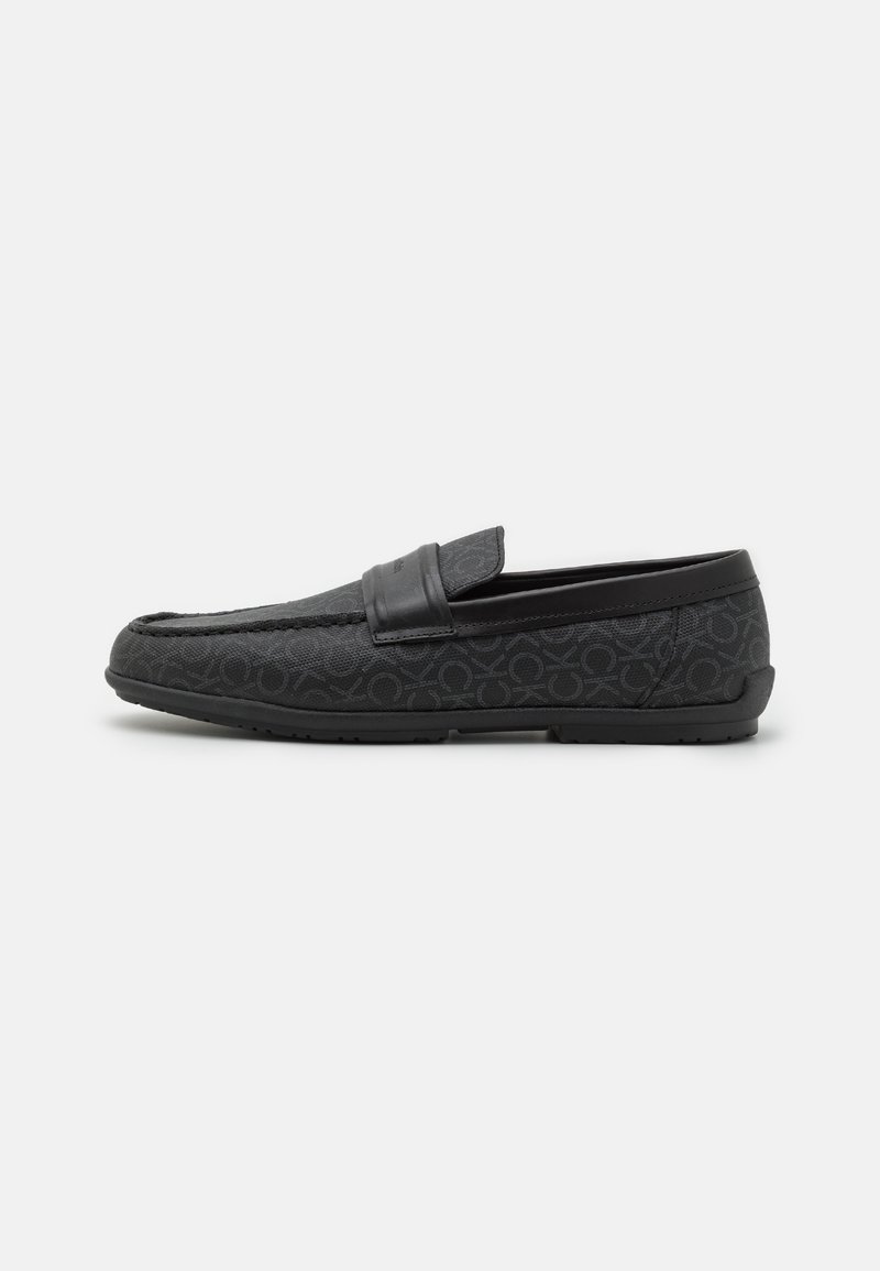 Mocassins noirs avec un tissu texturé arborant un motif subtil, une bride en cuir lisse sur le dessus, et une semelle en caoutchouc flexible.