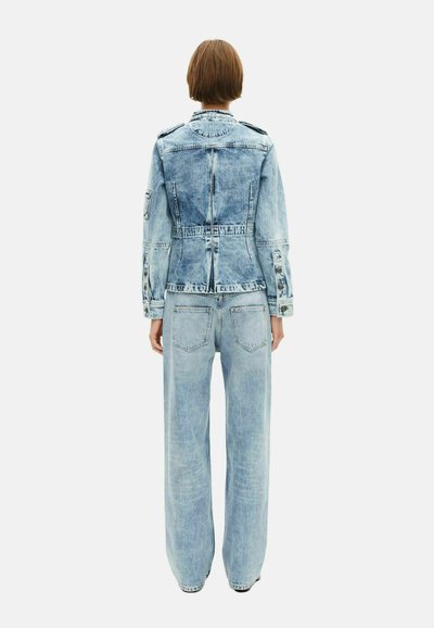 Veste en denim bleu clair avec une silhouette ajustée, associée à un jean bleu clair à jambes larges et décontractées. Texture déchirée sur les deux pièces.