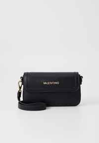 Borsa a tracolla in pelle nera con superficie texturizzata, hardware dorato, chiusura a patta e tracolla rimovibile. Nome del marchio impresso sulla parte anteriore.