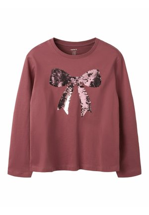 Chemise rose poudrée à manches longues avec un grand nœud brillant en sequins au centre, présentant des sequins réversibles roses et noirs.