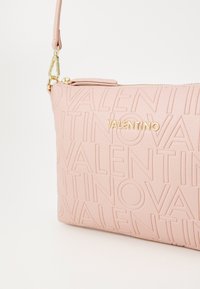 Bolsa de ombro em pele rosa com logo "VALENTINO" em relevo, detalhes em dourado e fecho com zip com uma alça removível.