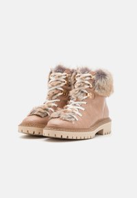 Bottes imperméables beiges avec bord en fourrure, lacets blancs et cuir texturé. Semelle en caoutchouc épaisse avec un cramponnage robuste pour une meilleure traction.