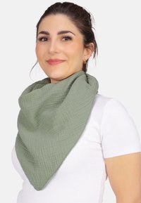 Foulard vert, texturé, en forme de triangle, fabriqué en tissu doux, drapé autour du cou, avec un motif en grille subtil et des bords bruts.