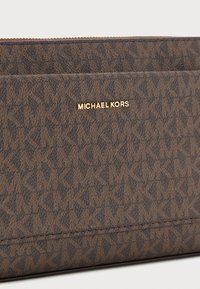 Brown Michael Kors wallet with textured MK monogram pattern and gold logo plaque on front panel.