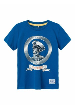 Camiseta de algodón azul con un gráfico de una calavera con sombrero de capitán, enmarcada en un timón circular, con una banda que dice "CAPITÁN" debajo.