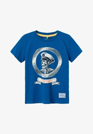 Camiseta de algodón azul con un gráfico de una calavera con sombrero de capitán, enmarcada en un timón circular, con una banda que dice "CAPITÁN" debajo.