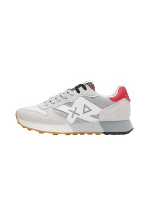 Baskets basses blanches et grises avec détails en daim, semelle en gomme, lacets noirs et gris, languette de talon rouge, et logo latéral blanc comportant des formes en X et en triangle.