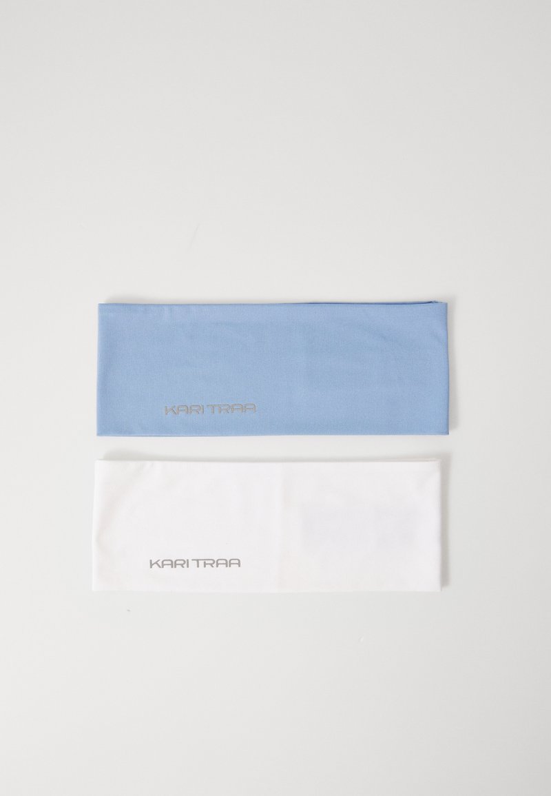 Dos diademas, una en azul claro y otra en blanco, hechas de un material liso y elástico. Ambas presentan "KARI TRAA" en letras plateadas.