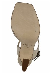 Sandalo alto in suede beige con design aperto, cinturino alla caviglia regolabile e punta affusolata. Suola piatta con un accento marrone. Taglia 37.