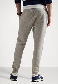 Grå sweatpants i bomullsblandning, med en tapered design, elastisk midja och en bakficka. Bärs med blå sportskor.