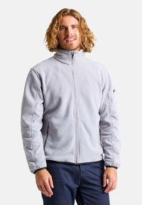 Giacca in pile grigio chiaro con colletto alto, zip frontale e tasche laterali con zip. Presenta accenti a contrasto sui polsini.