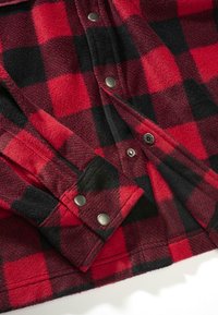 Rotes und schwarzes kariertes Flanellhemd mit Druckknöpfen, das eine weiche Textur und einen abgerundeten Saum aufweist. Deutliches Karomuster über den gesamten Stoff.