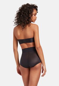Svart strapless shapewear med en slät tygkvalitet, hög midja, genomskinliga detaljer och säker krok-och-öga stängning bak.