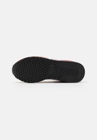 Suola di una scarpa in gomma nera con un motivo di presa testurizzato. Presenta una sezione superiore rosa che si fonde nel design della suola.