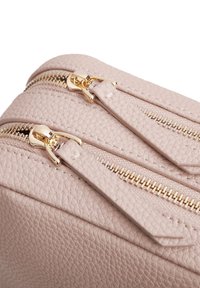 Borsa in pelle rosa con superficie rigata e due chiusure lampo dorate. Caratterizzata da due tiranti delle zip con estremità piatte per una facile maneggevolezza.