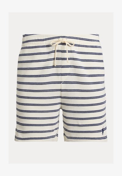 Csíkos fürdőnadrág krémszínben és tengerészkékben, szövött textúrával, húzózsinóros derékrésszel és egy kis logóval az alsó szegélyen.
