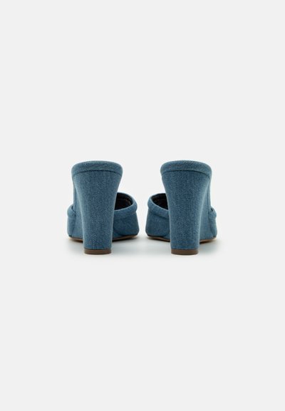 Mule din denim cu toc gros înalt, având vârful rotunjit și spatele expus. Material texturat de culoare albastră cu un finisaj neted.